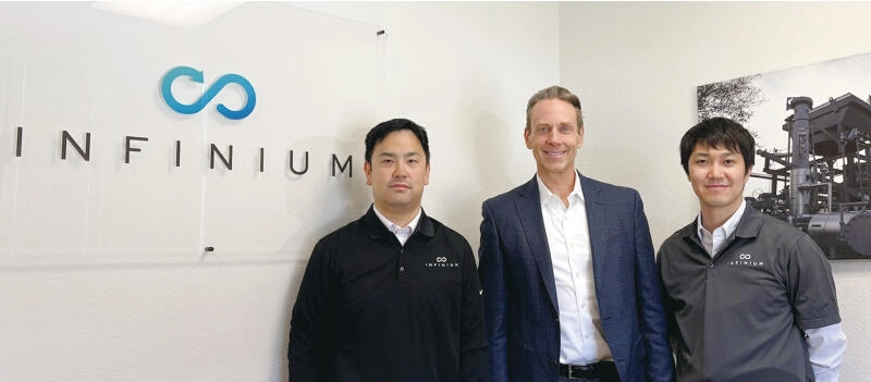 Infinium Holdings, Inc.のロゴを背に並ぶ、同社CEOのRobert Schuetzle氏と、日本政策投資銀行(DBJ)の担当者。