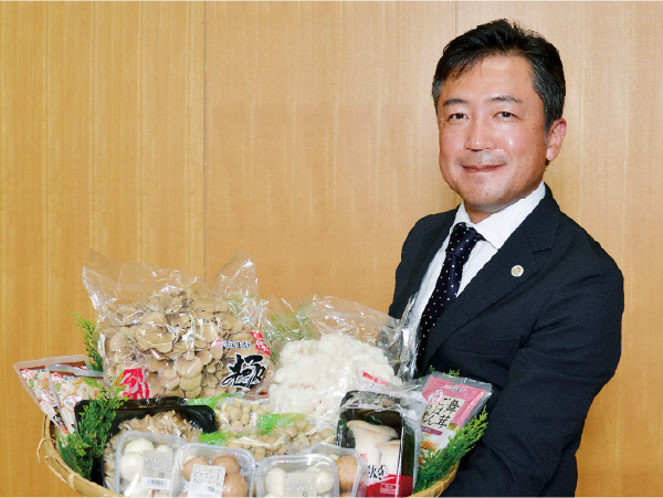 「極（きわみ）」などのまいたけや、エリンギ、しめじ、マッシュルームといった自社製品の詰め合わせを手にする、株式会社雪国まいたけ　代表取締役社長　湯澤尚史氏